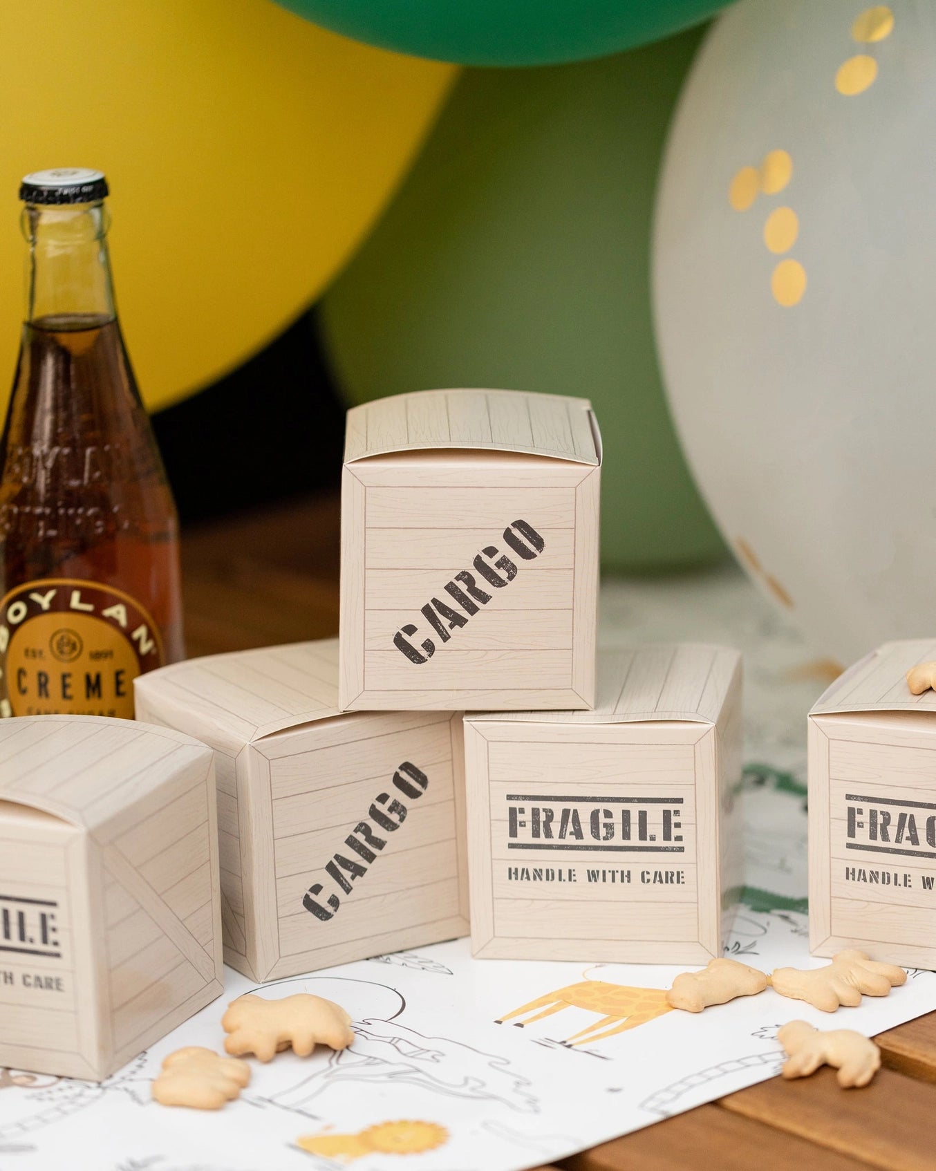 Jungle theme party favor boxes styled as cargo crates with safari-themed decor and cream soda bottle.