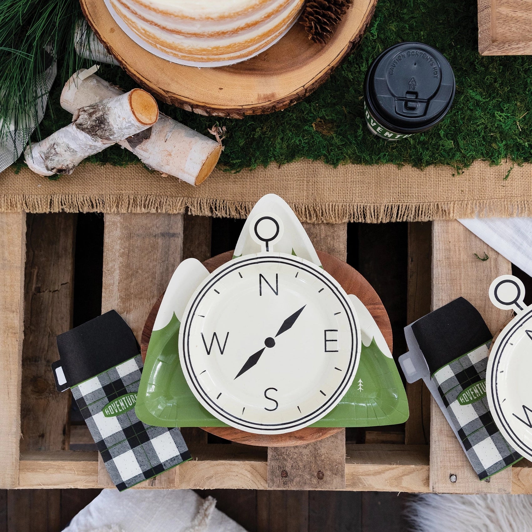 Thermos napkin placed beside a compass plate on a rustic table with pine accents and wood slices—perfectly themed for a nature-inspired birthday.