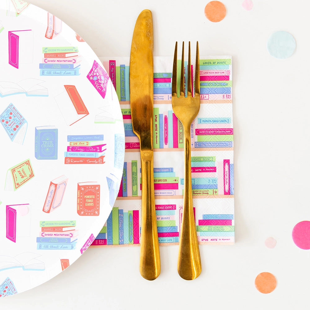 Gold knife and fork on pastel book spine napkin beside 10-inch dinner plate covered in colorful illustrated books.