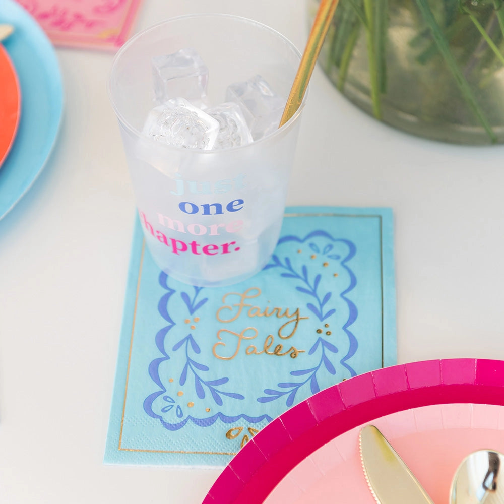 Charming blue 'Fairy Tales' cocktail napkin placed under a cup encouraging 'Just one more chapter.'