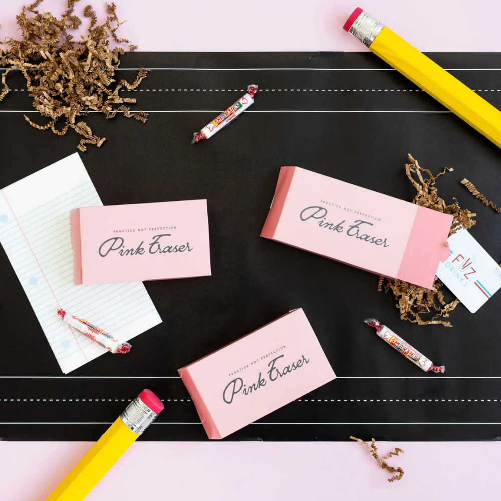 Styled flat lay of assembled eraser boxes with school-themed props.