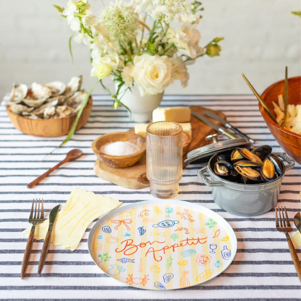 Striped tablecloth with mussels, butter, and Le Dinner Bon Appetit Dinner Plate ready for a seafood meal.