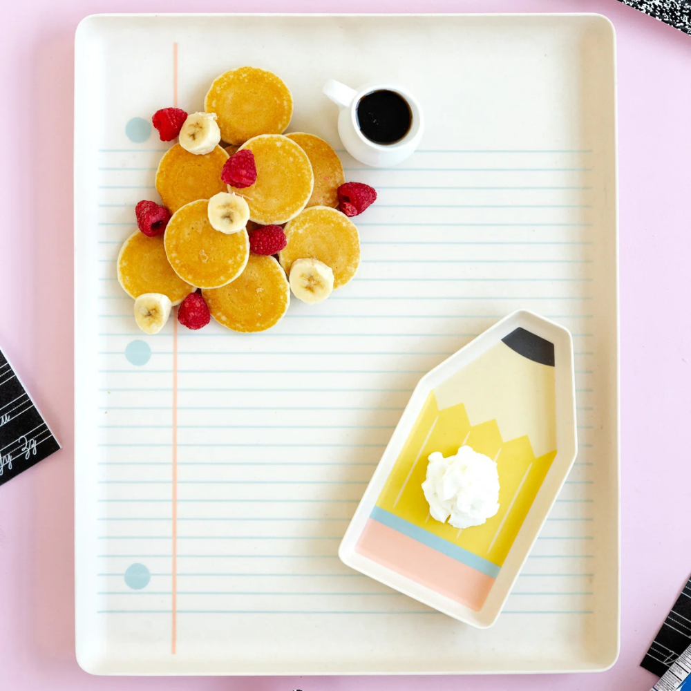Bamboo trays filled with pancakes, fruit, and syrup for breakfast