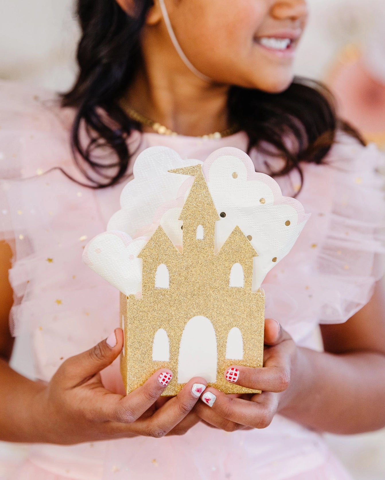 Close side view of smiling girl holding assembled princess castle favor box at a princess birthday party.