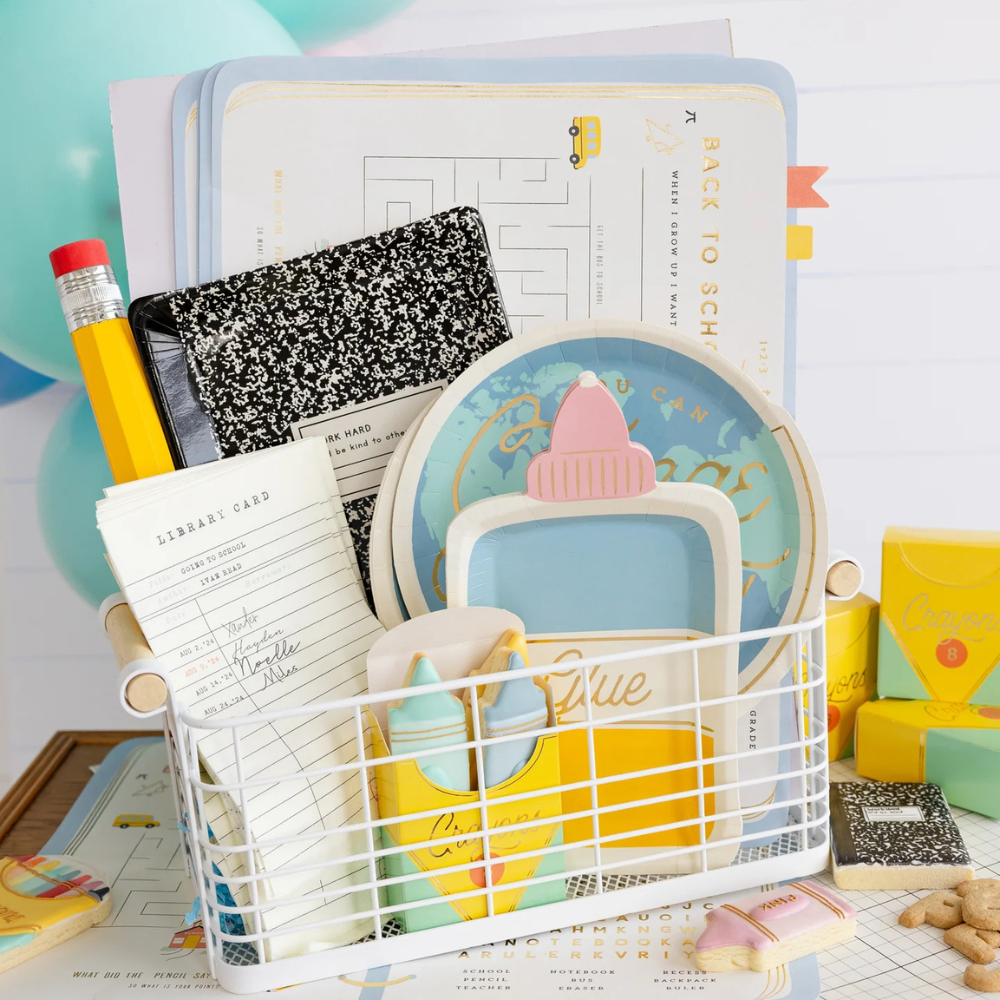 Close-up of a wire basket filled with back to school paper goods, including the library card napkin, plates, and composition notebooks.