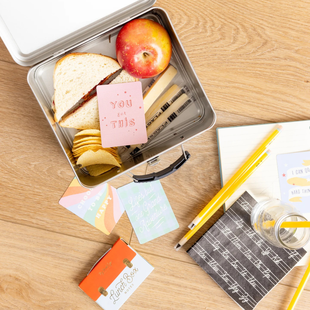 Napkin styled in lunchbox scene with sandwiches, snacks, and lunchbox notes