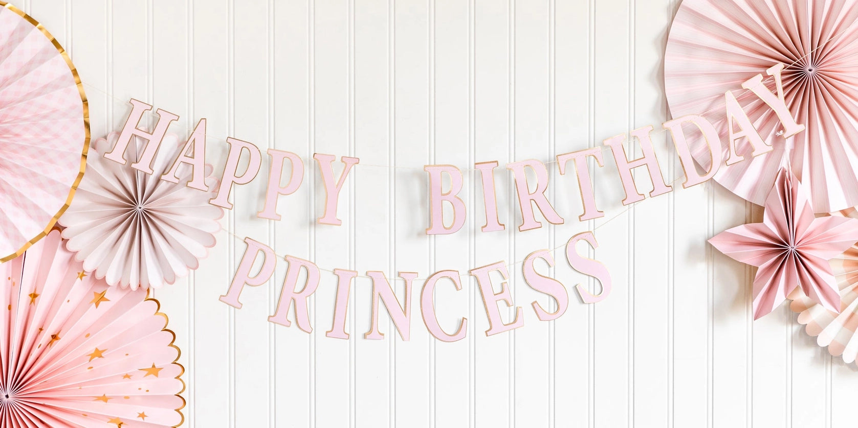 HAPPY BIRTHDAY PRINCESS banner on beadboard wall, framed by pastel rosette fans and star accents.