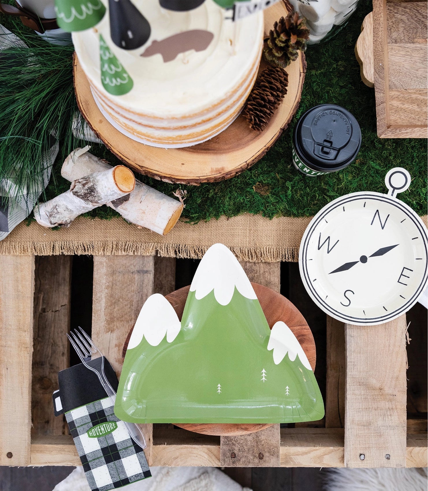A styled party setup featuring the green mountain plate on a wooden charger, surrounded by adventure-themed décor.