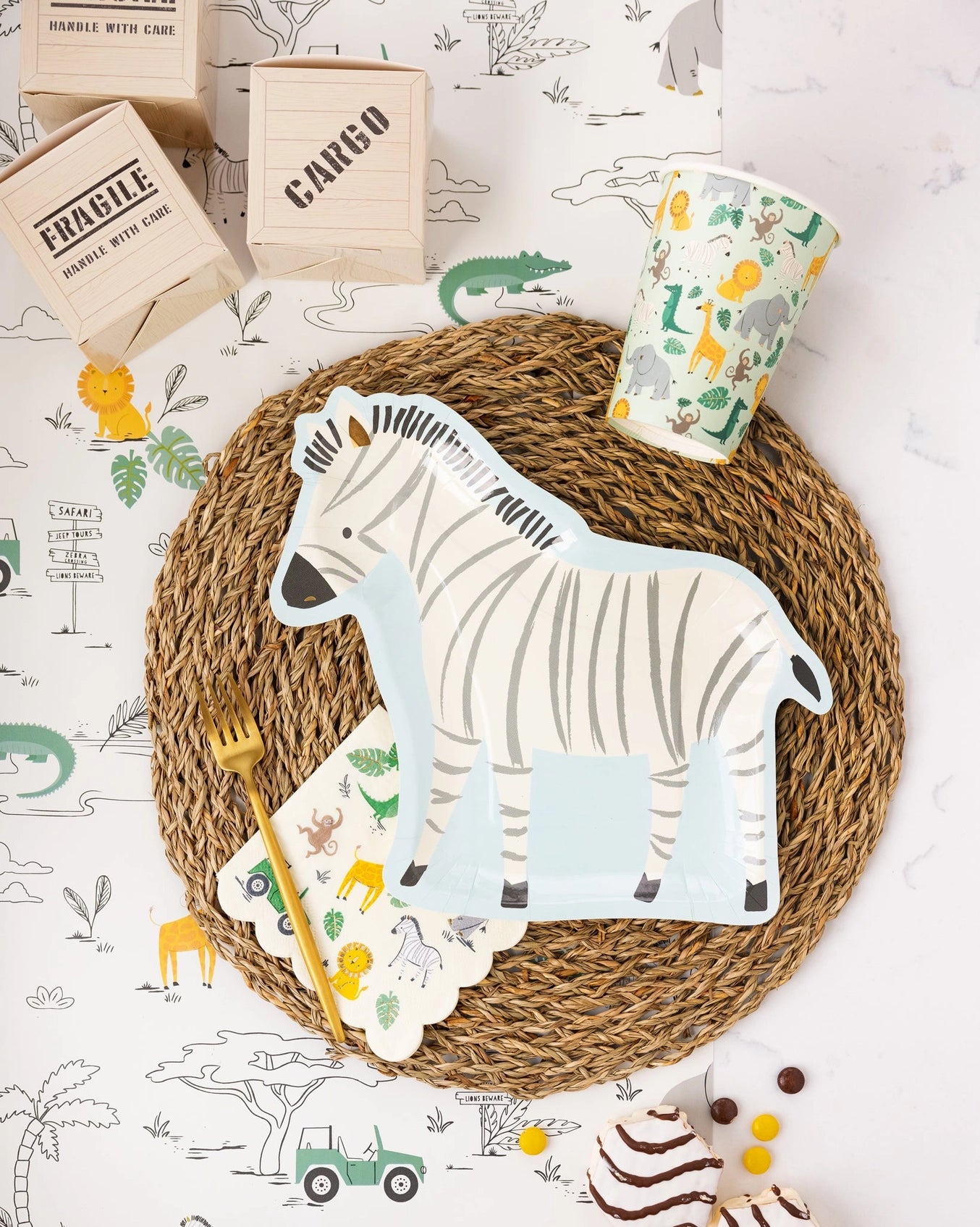Safari-themed place setting featuring zebra plate, animal-printed cup, jungle napkin, and cargo-style treat boxes.