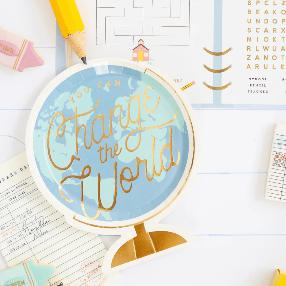 Top-down view of a globe-shaped plate and back to school activity placemat, with a library card napkin tucked underneath.