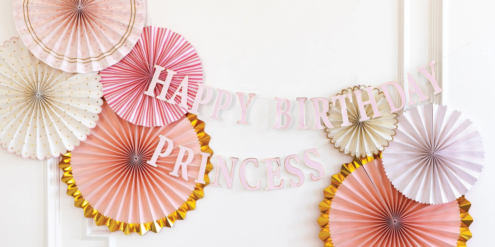 Close-up wall shot of banner draped across layered blush and gold fans—perfect for a princess birthday party backdrop.