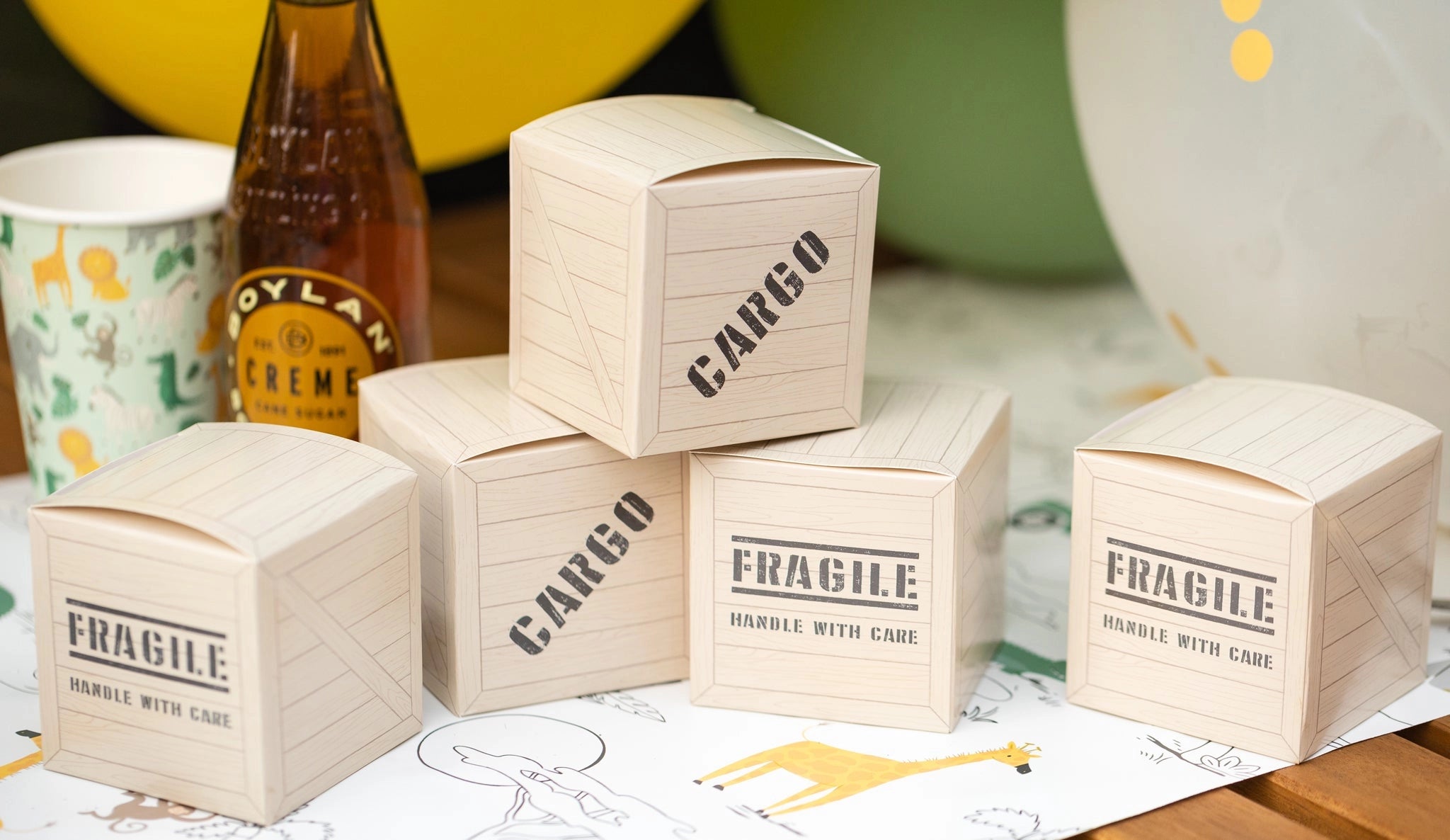 Jungle theme party favor boxes styled as cargo crates with safari-themed decor and cream soda bottle.
