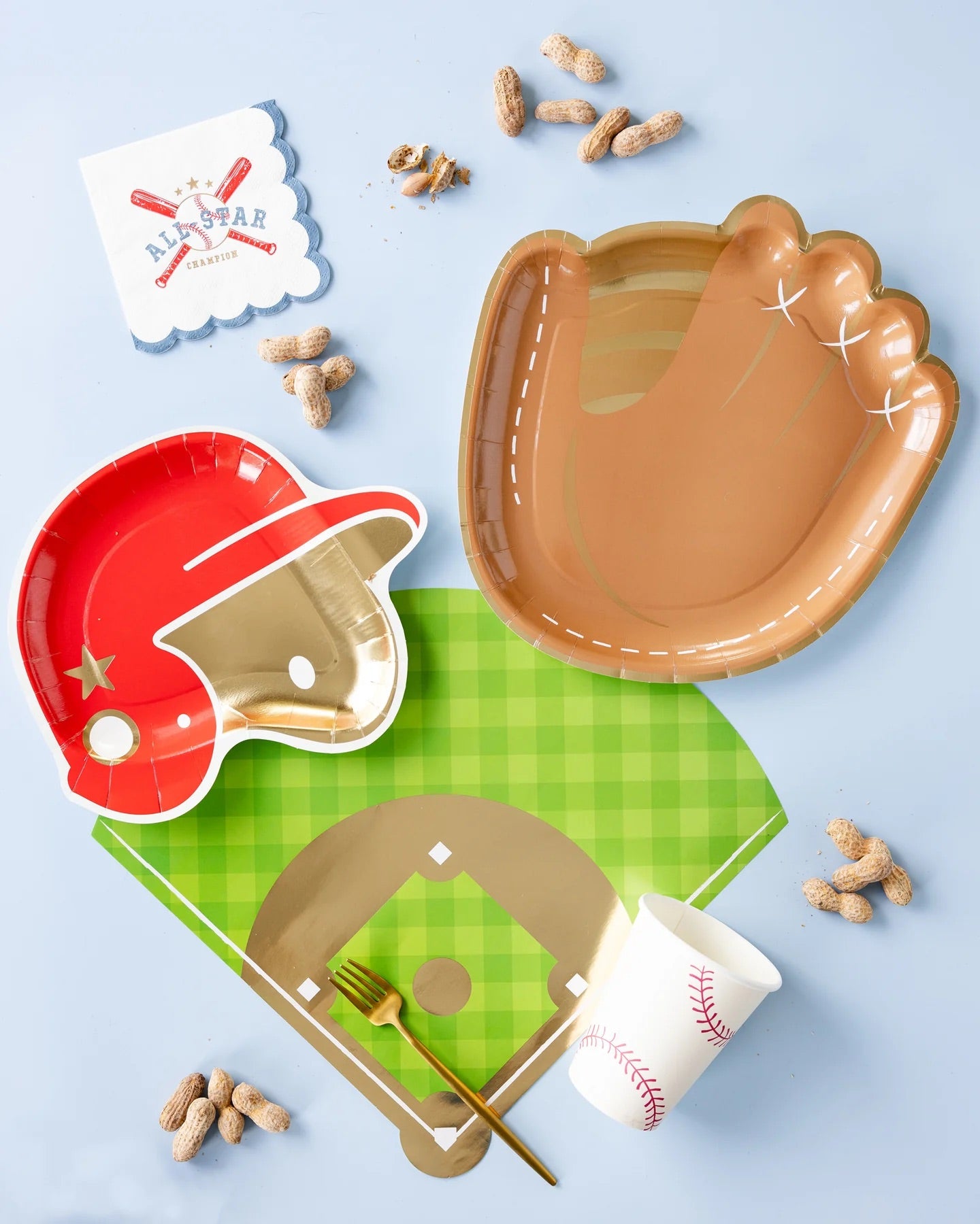 Baseball party spread showcasing All Star cocktail napkins, baseball glove-shaped plates, and a bright green baseball diamond placemat with peanuts scattered around.