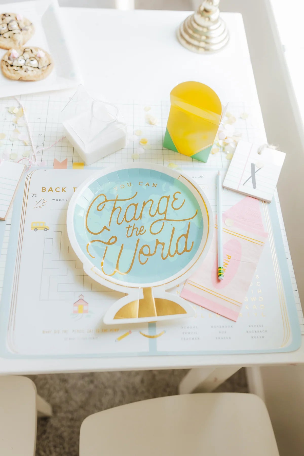 Children's place setting with cookies and globe plates atop planner placemats.