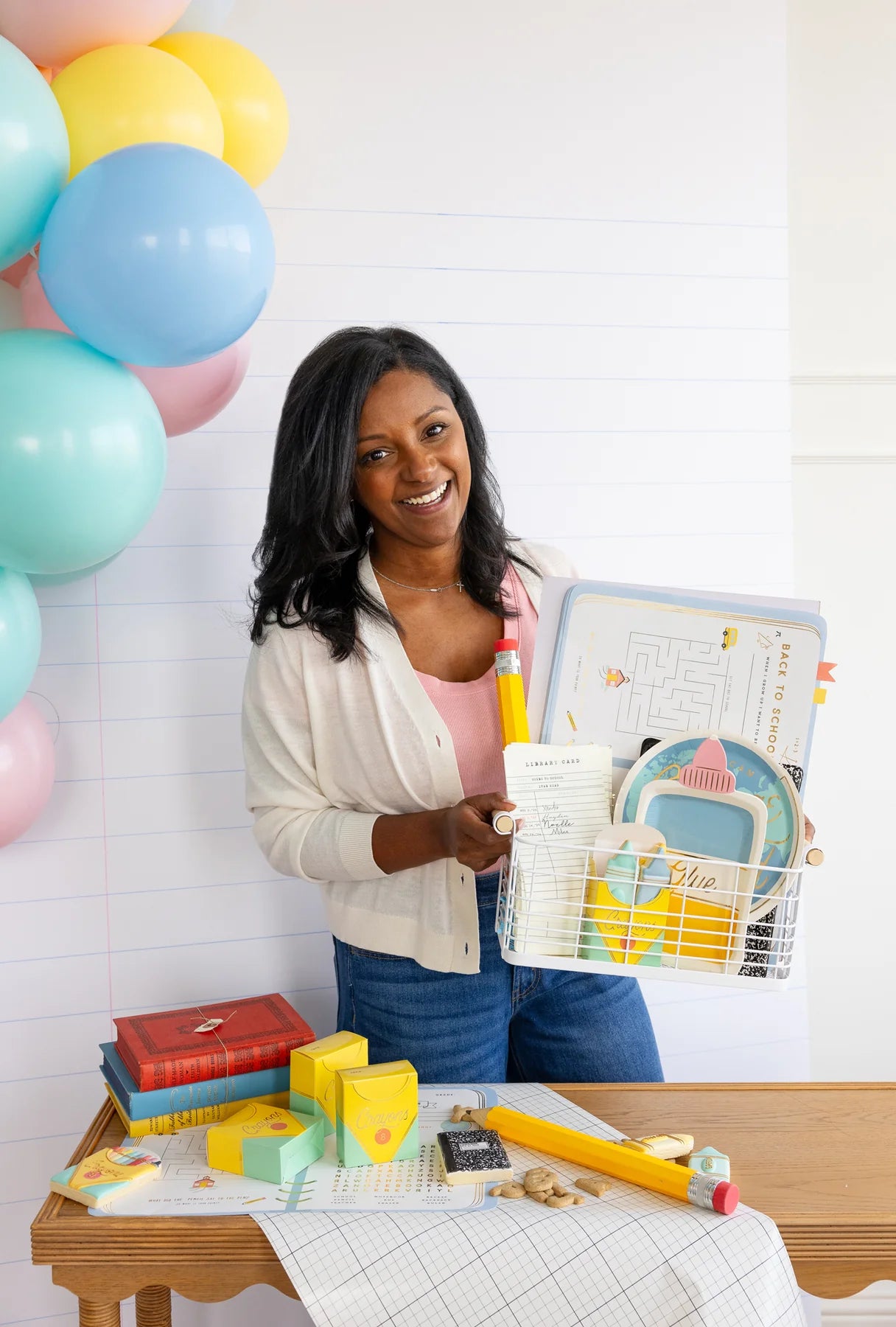 Smiling mom holding a wire basket filled with back to school decorations including the placemats.