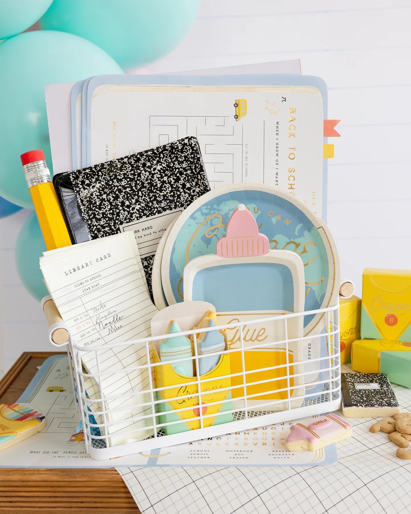 Basket filled with school-themed party supplies and a peek of the planner placemats underneath.