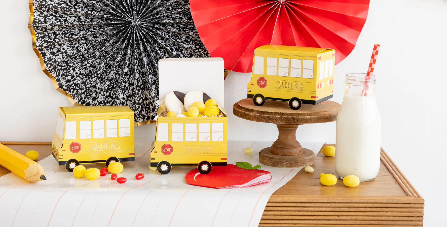 Apple napkins styled on a table with milk bottle, school bus boxes, and pencil props.