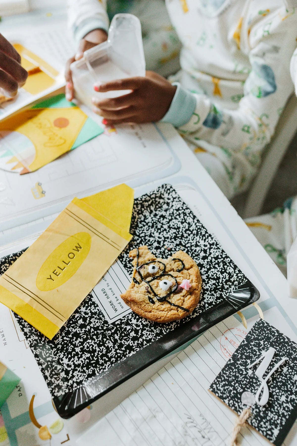 Close-up of cookie on top of comp notebook plate with yellow crayon napkin