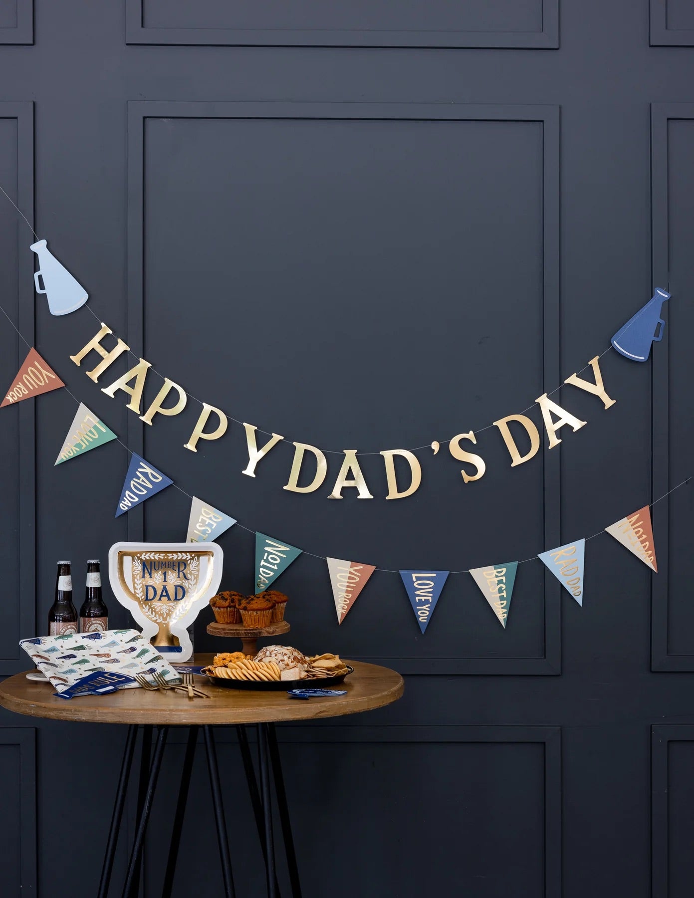 Father’s Day party setup – A festive party setup with the Father's Day banner hanging on a dark blue wall, a snack table, and a trophy-shaped plate for Dad.