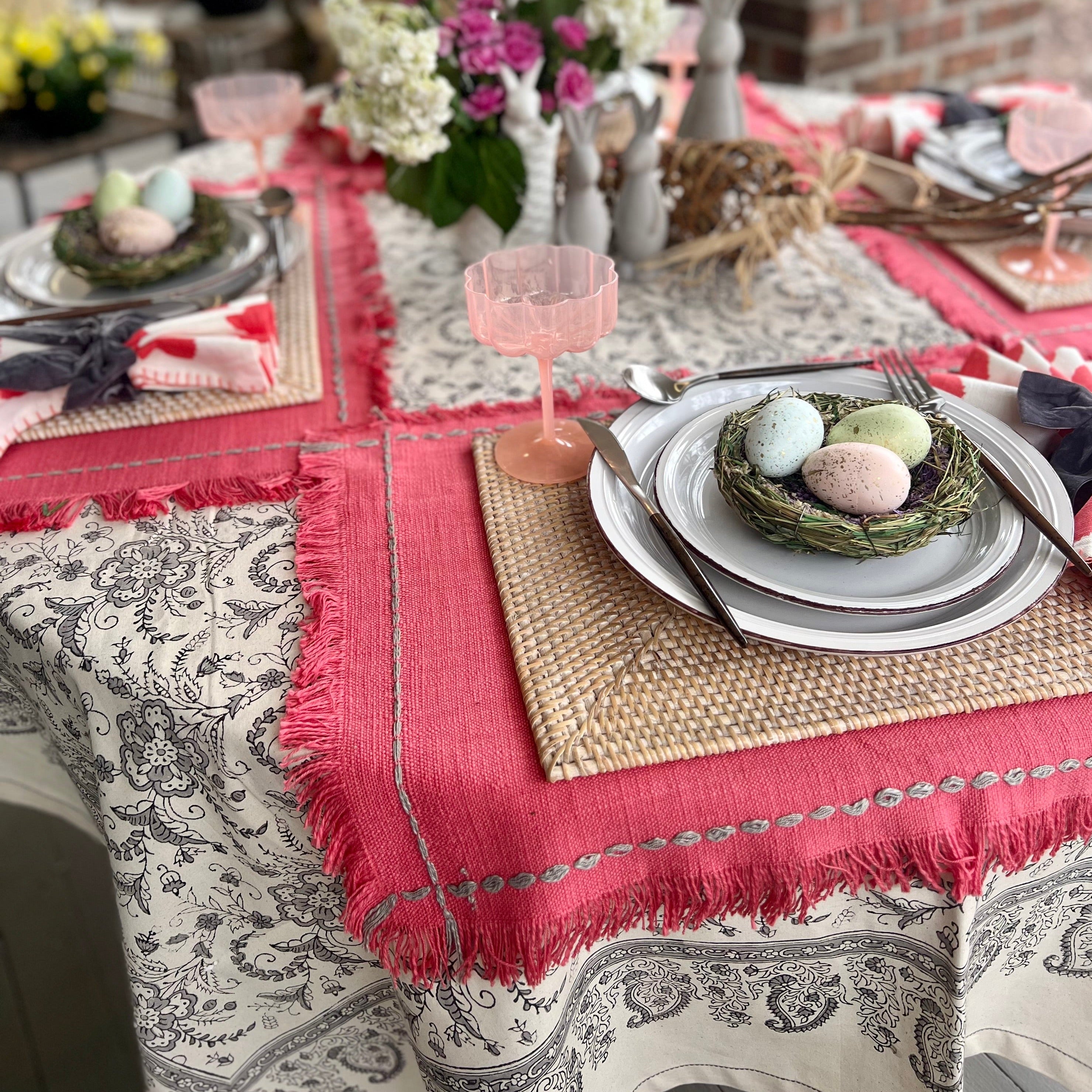 Off-white tablecloth with a gray floral design set with an Easter tablescape.