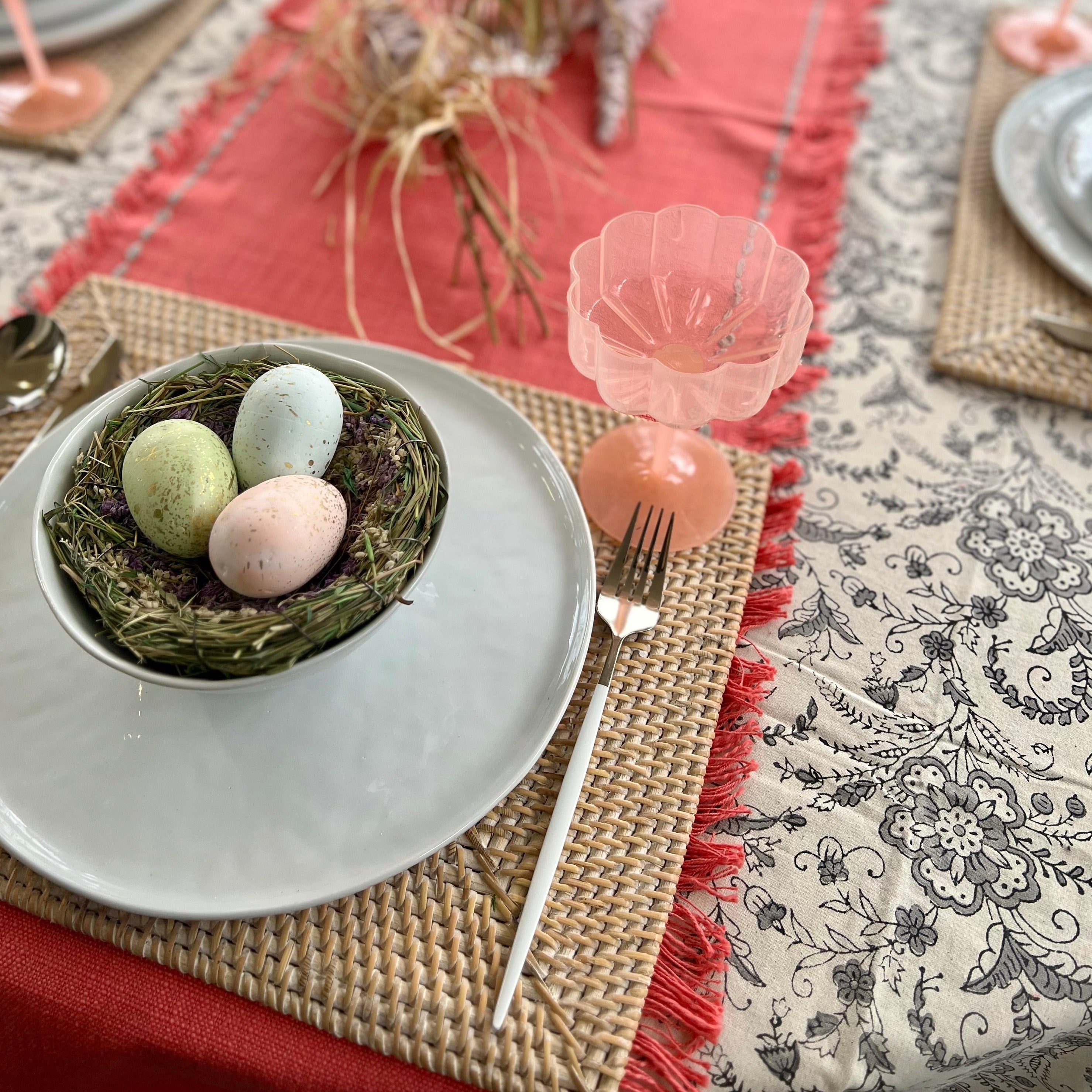 Rectangle rattan placemat in a white wash color on an Spring table. The perfect gift for someone who enjoys hosting.
