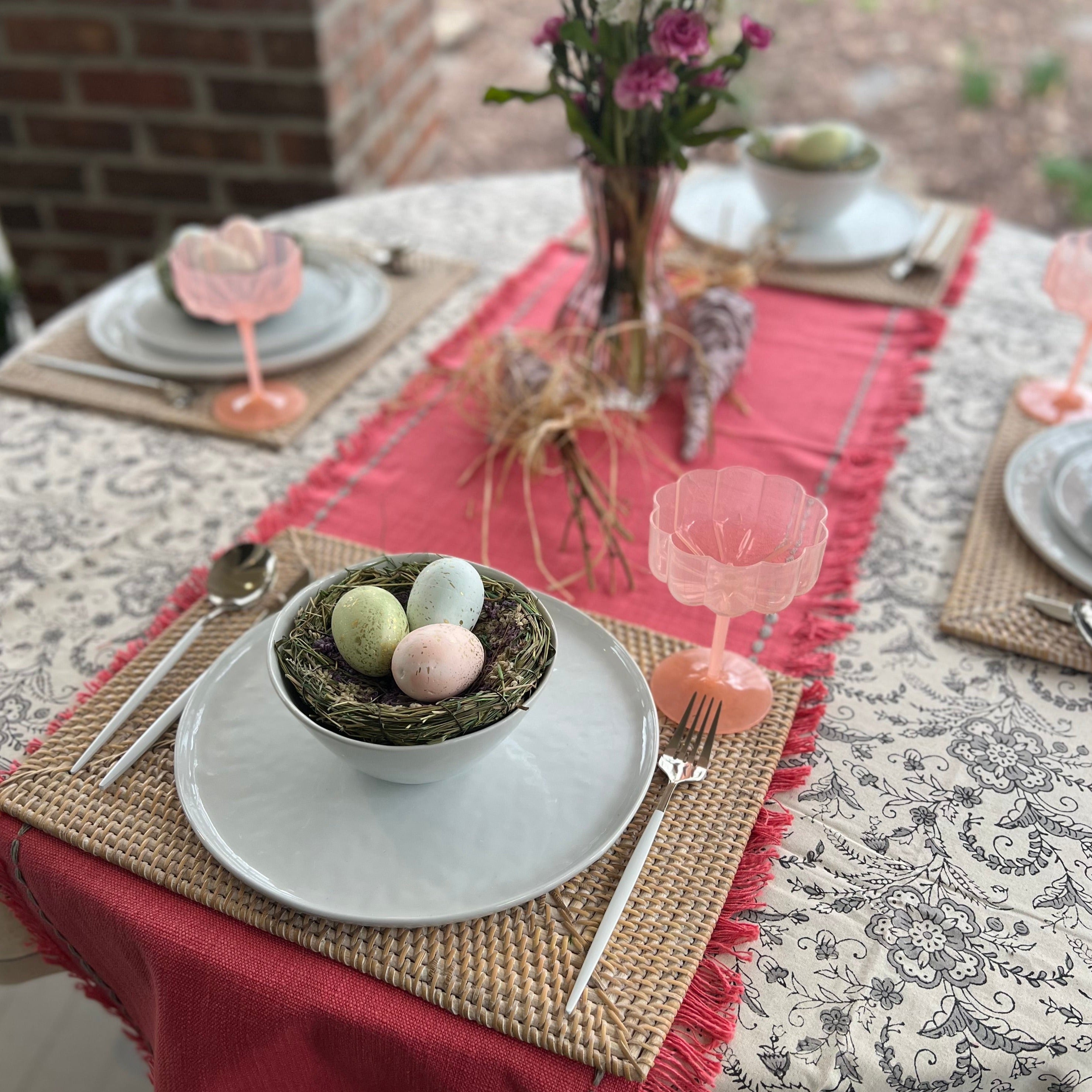 Rectangle rattan placemat in a white wash color on an Spring table. The perfect gift for someone who enjoys hosting.