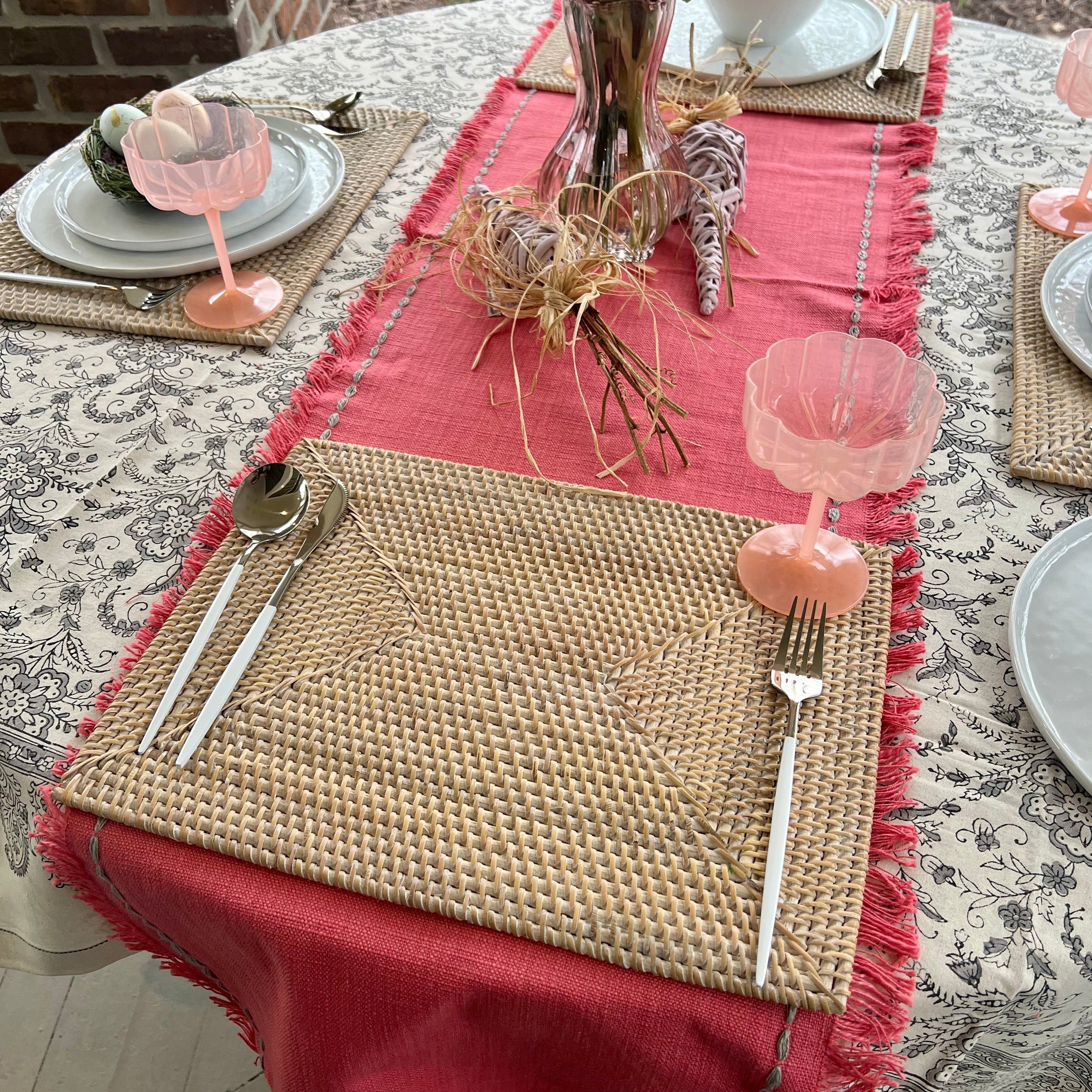 Rectangle rattan placemat in a white wash color on an Spring table. The perfect gift for someone who enjoys hosting.