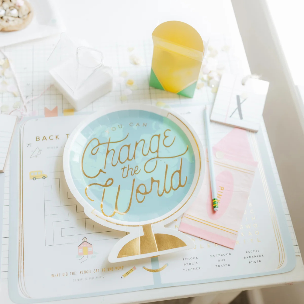 Back to school place setting featuring a globe-shaped plate, pink crayon napkin, and themed decorations.