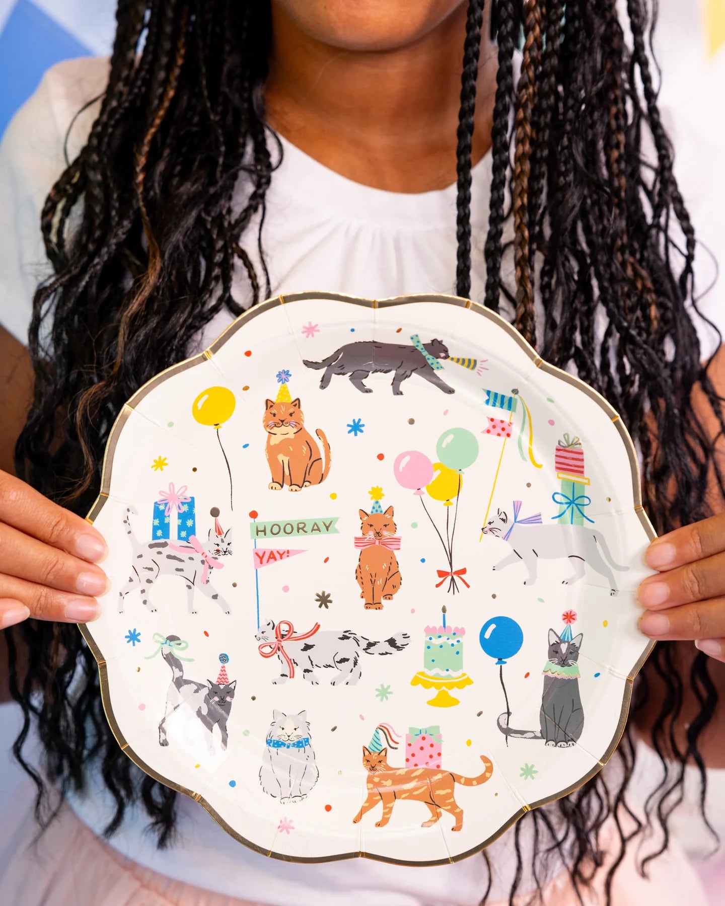 Close-up of party guest holding a Cat Party Plate, highlighting the playful kitty illustrations and shiny gold edge.