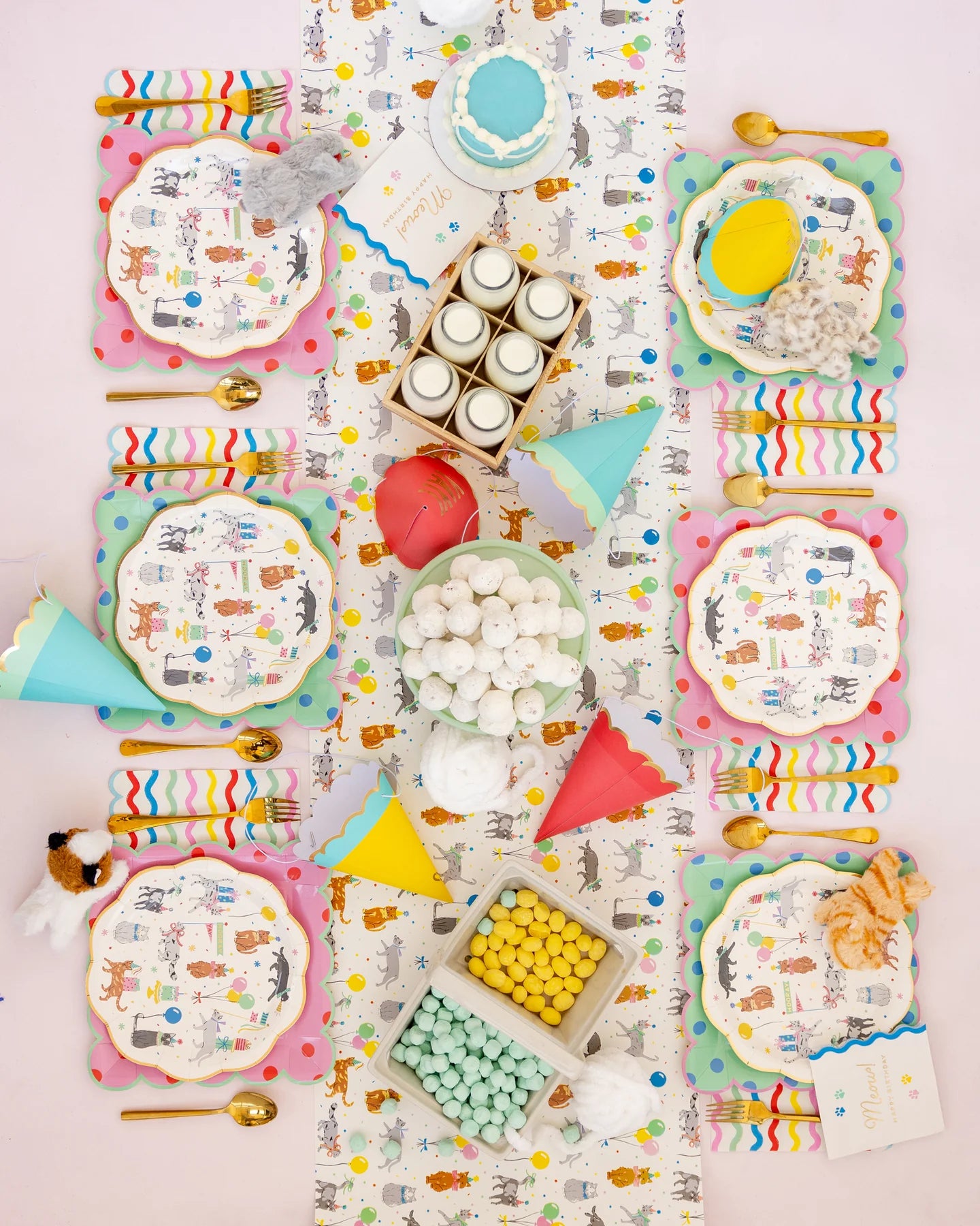 Overhead view of a full cat birthday table runner lined with multiple Cat Party Plates, treats, and yarn-ball décor.