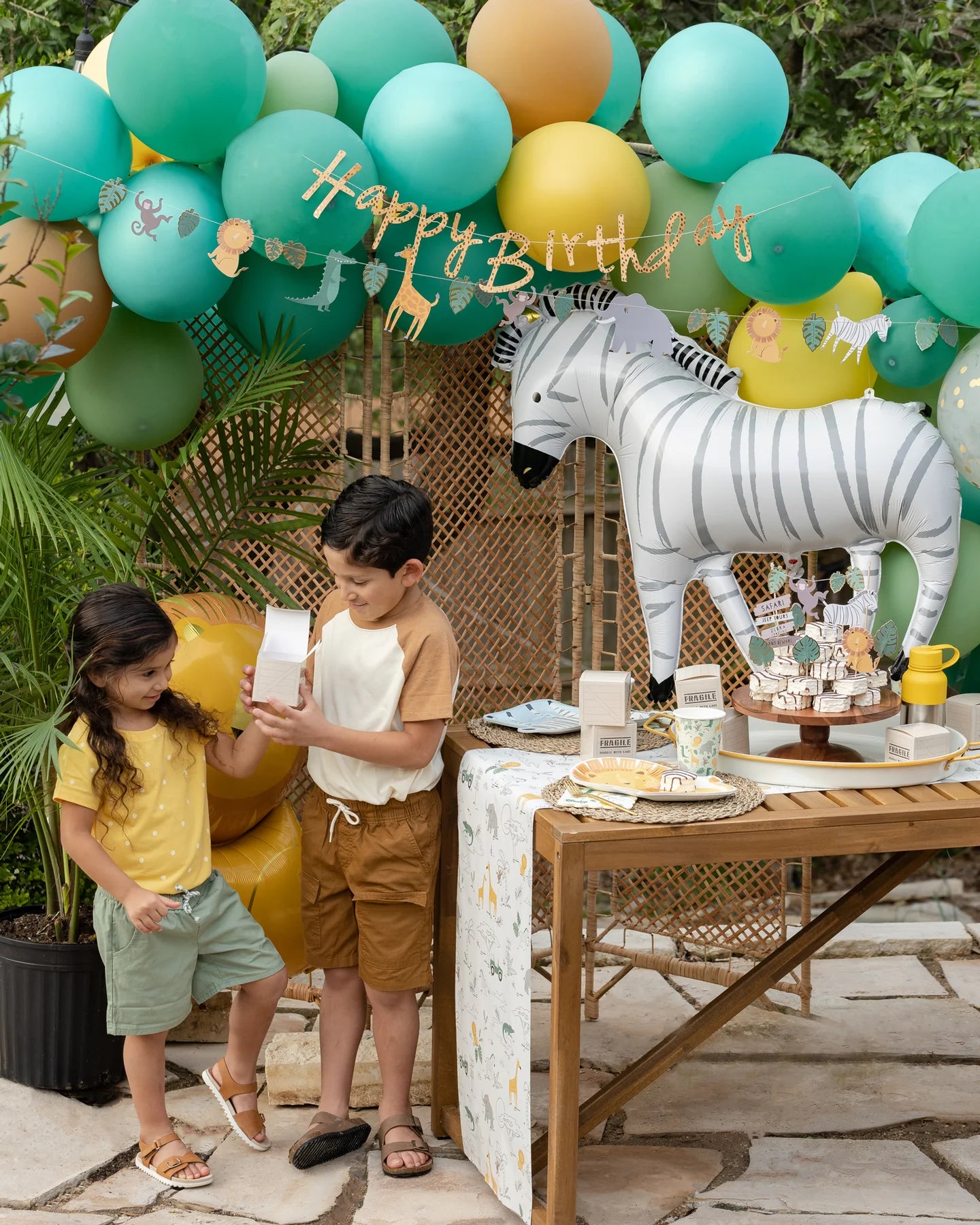 Kids enjoying a jungle theme birthday party setup, featuring balloons, zebra balloons, and safari decor.