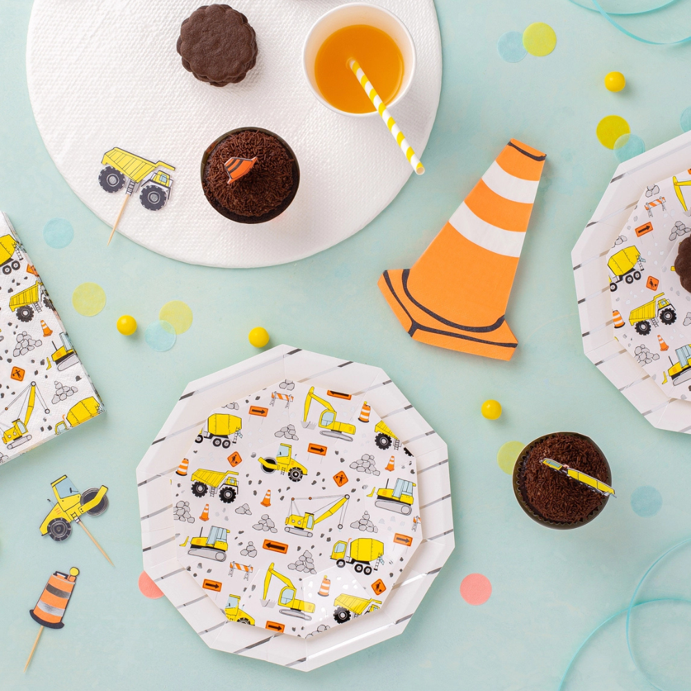 Overhead view of construction-themed party setup featuring octagonal plates, chocolate cupcakes, and traffic cone napkins.