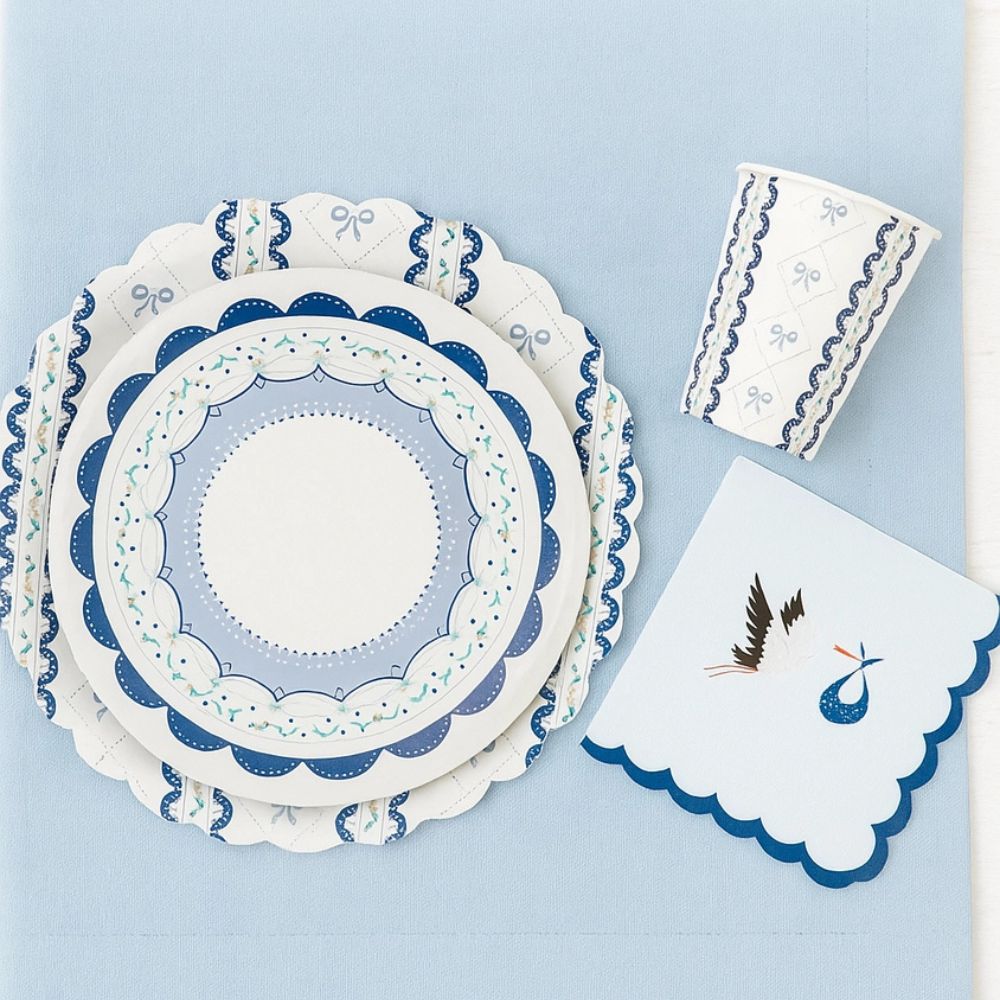 Overhead flat lay of blue ribbon tableware set with a scalloped stork napkin