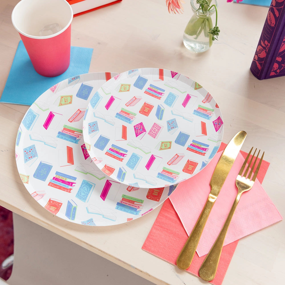 Angled shot of two stacked dessert plates displaying pastel book stacks next to gold fork and knife.