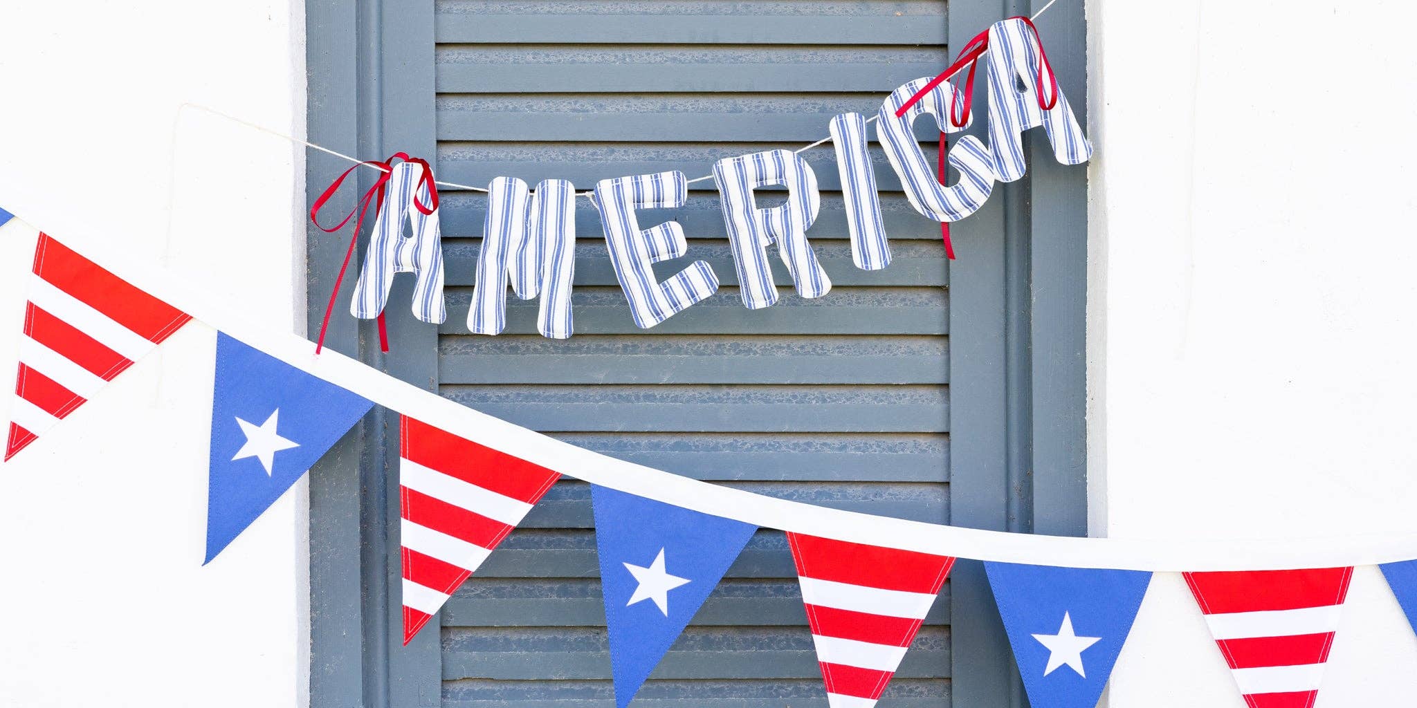 Navy ticking stripe America banner hung on blue shutters above red white and blue star pennant bunting