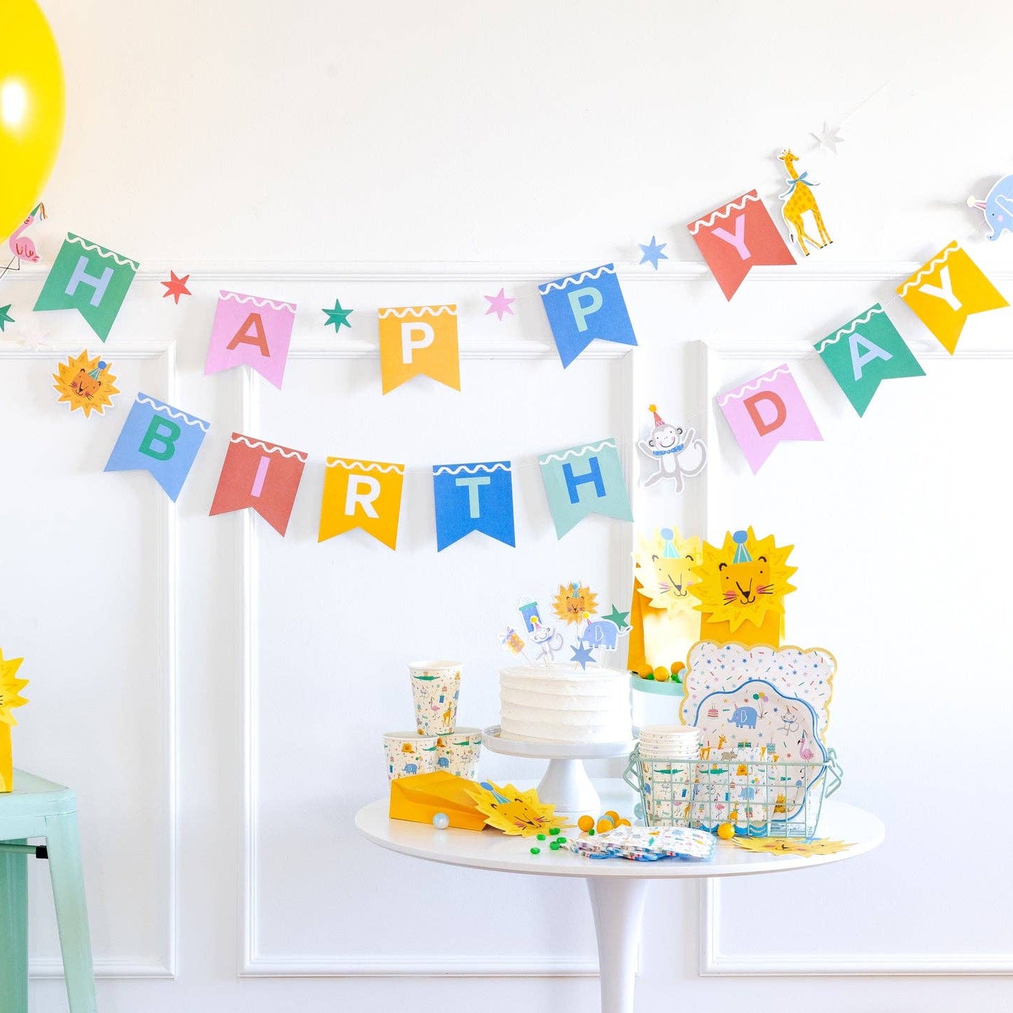 Animal party birthday setup featuring banner, plates, cups, and decorations.