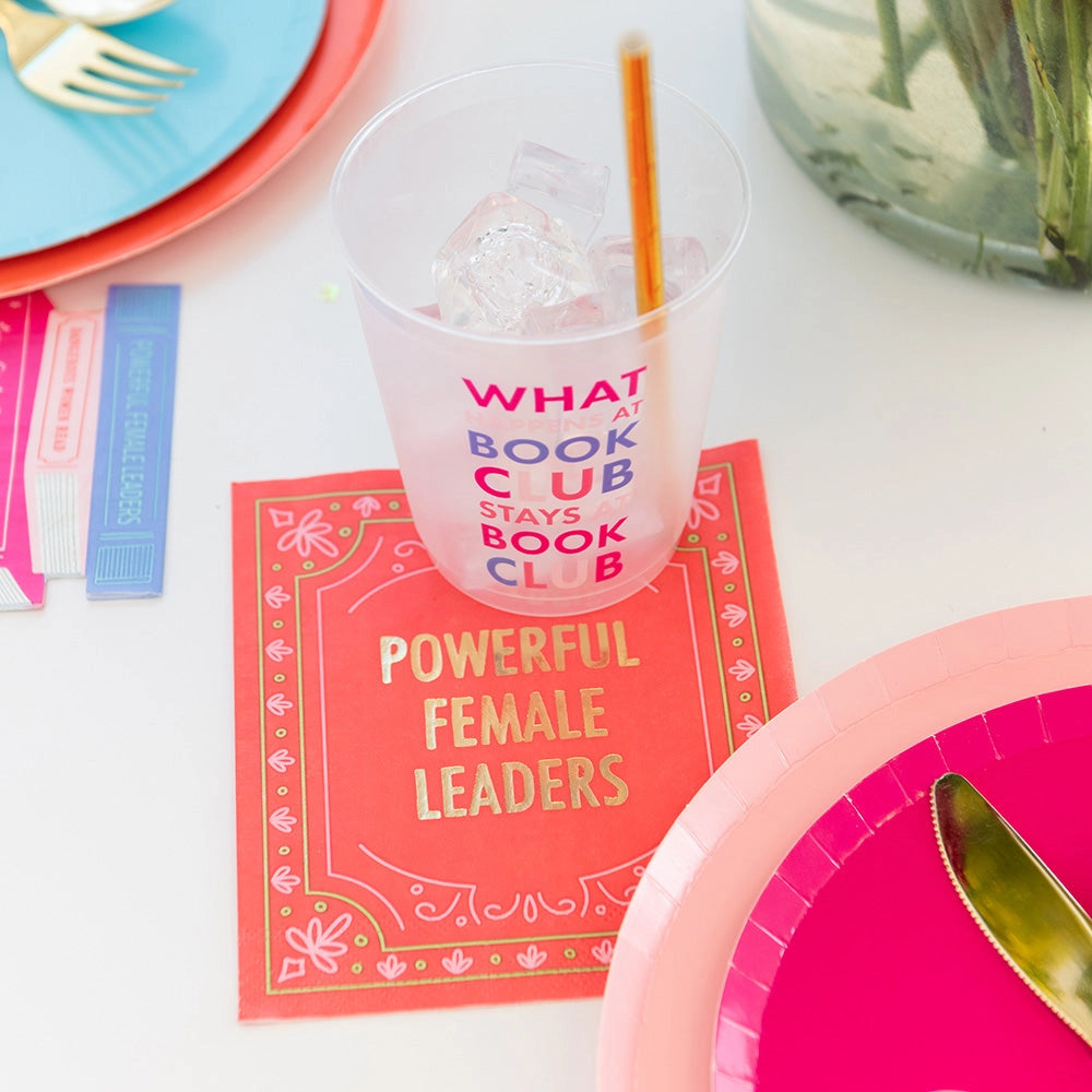 Vibrant red 'Powerful Female Leaders' cocktail napkin alongside a playful book club-themed cup