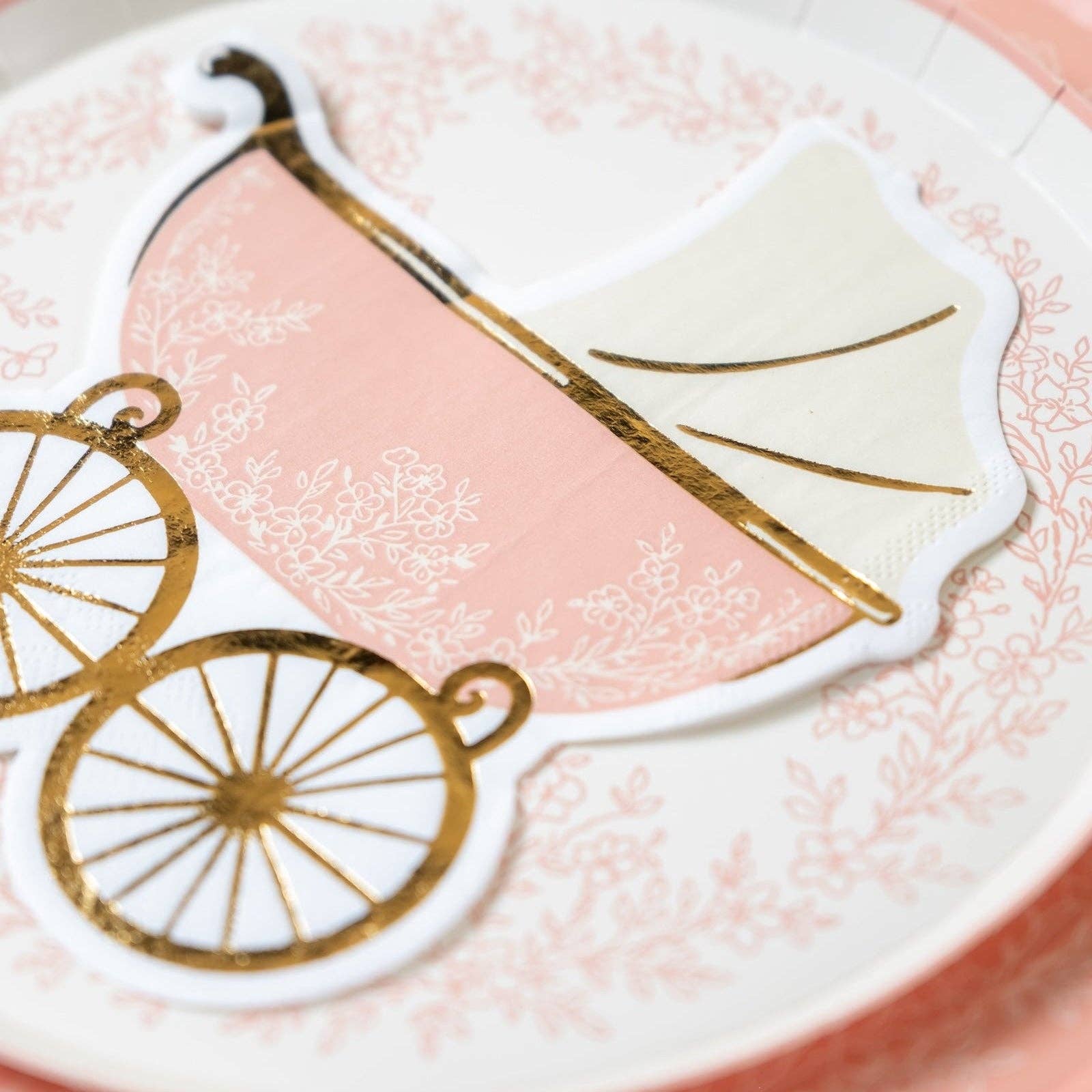 close up of stroller shaped baby shower napkin on floral plate
