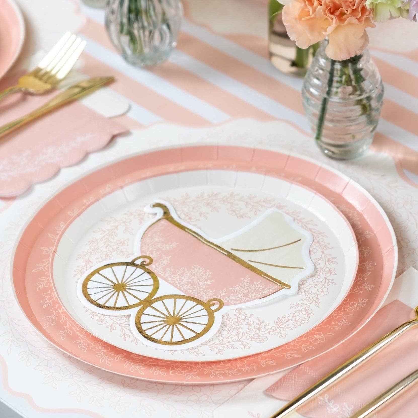 Pink striped table runner with carriage plate, flowers, and gold utensils
