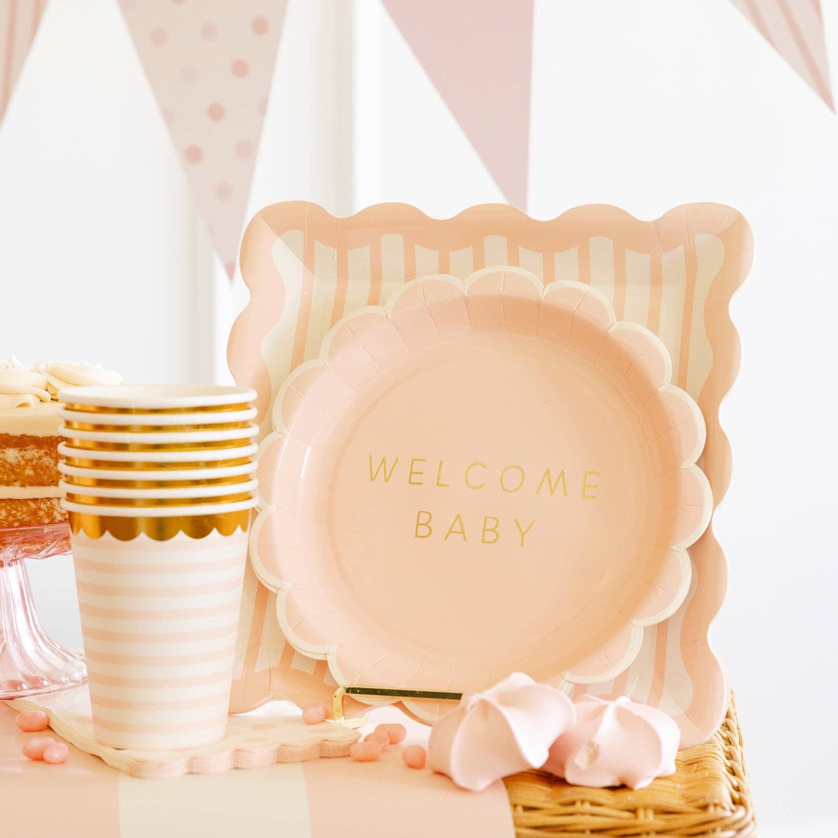 Baby shower table with pink striped cups and welcome baby plates