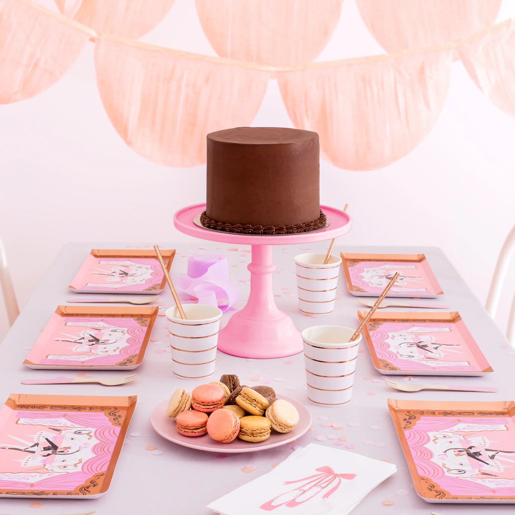 High-end balletcore birthday table with a chocolate cake on a pink stand, ballerina plates, and tutut guest napkins.