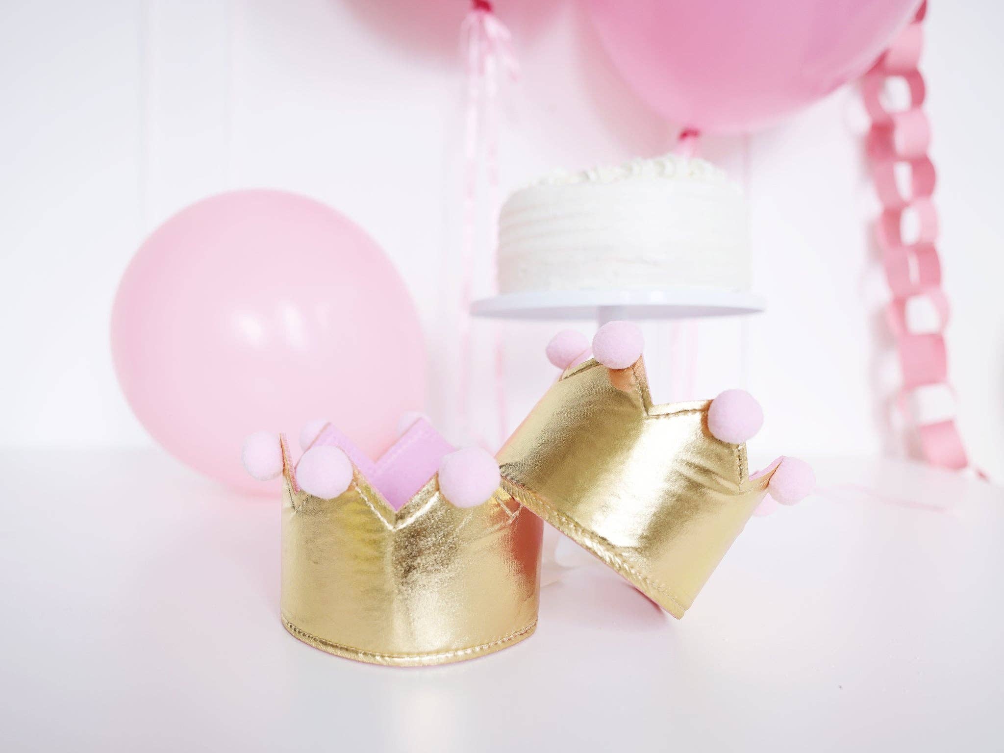 Two gold and pink birthday crowns styled on a table for a Vintage Princess Aesthetic.