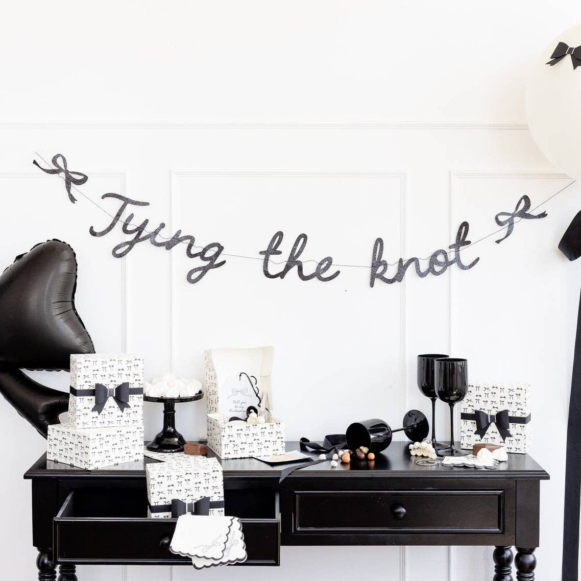 Table styling image with cake: Black bow cocktail napkins styled on elegant black and gold dessert table with cake