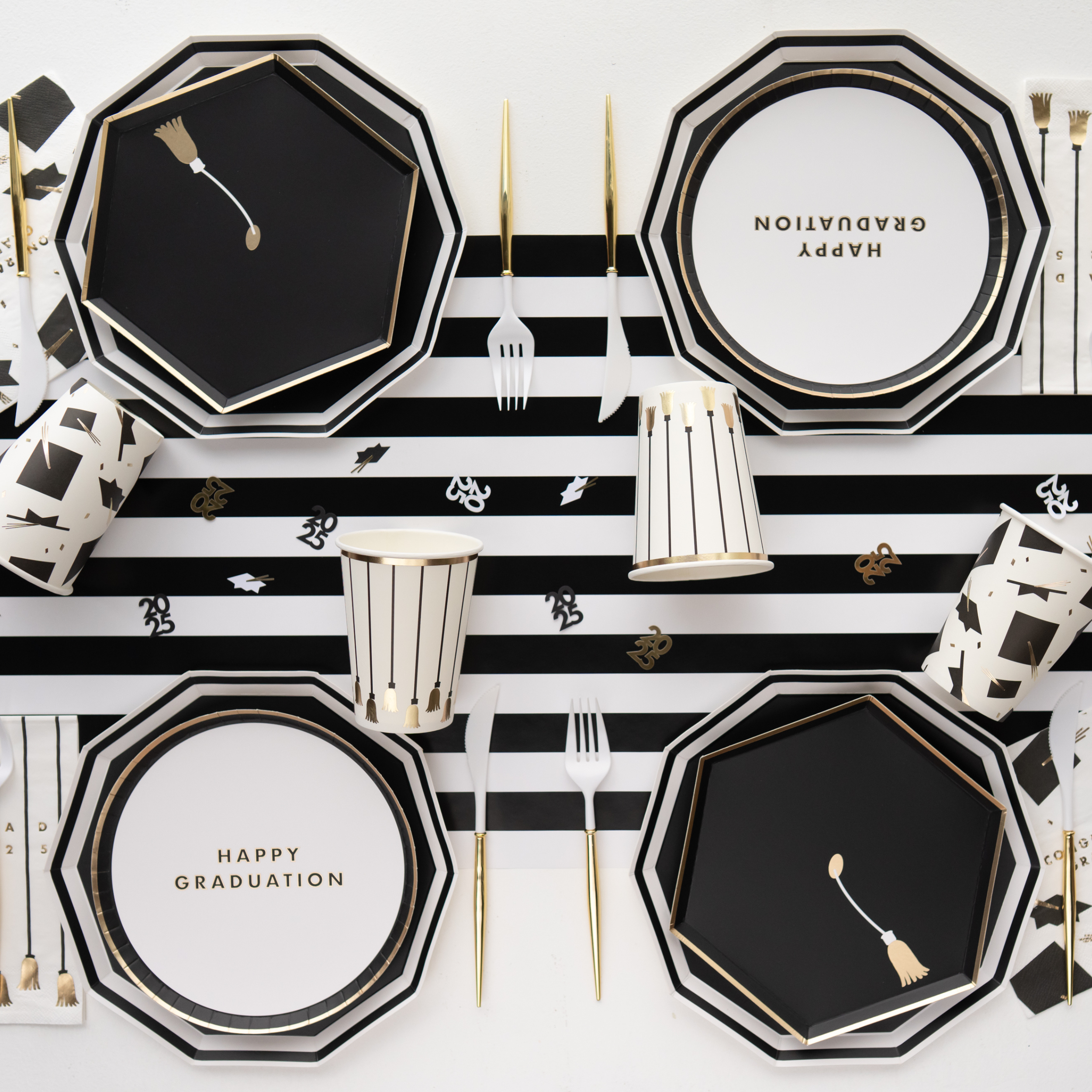 Black and white graduation party table setup with decagon plates and striped tablecloth
