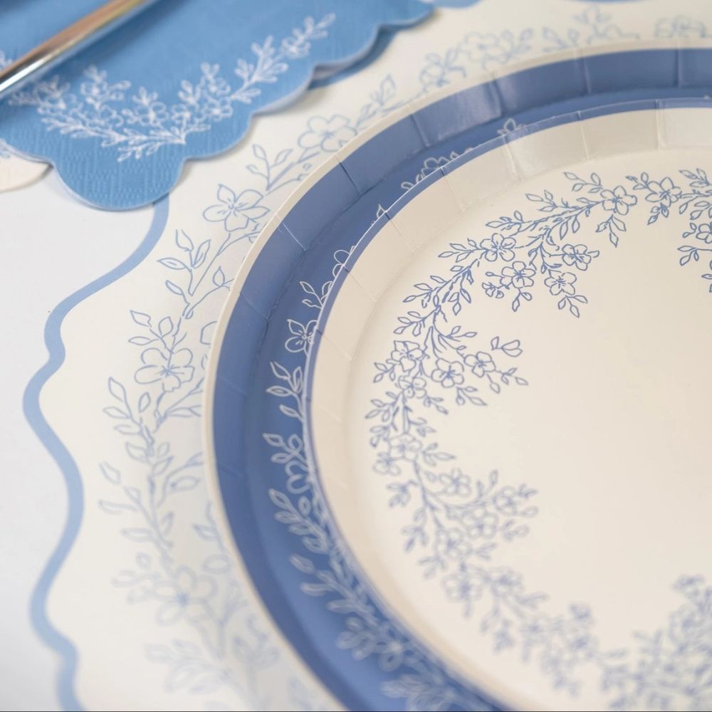 close up of blue floral placemat with scalloped edge and botanical detail.