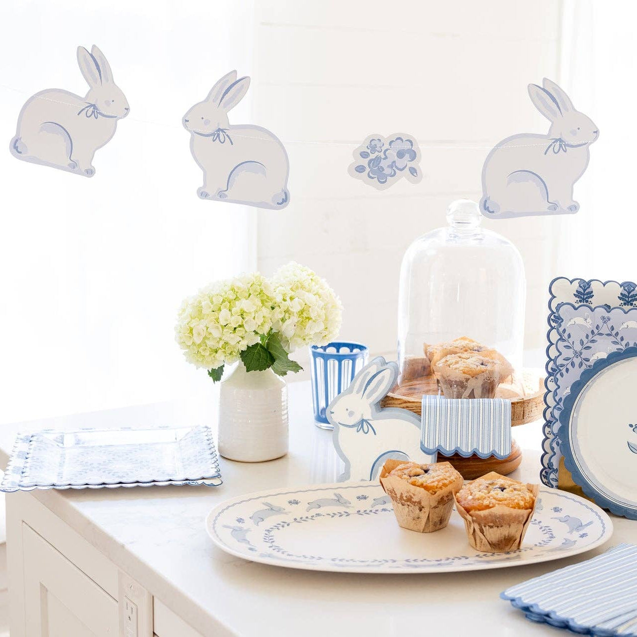 Blue bunny banner styled above a spring dessert table with Easter decorations.
