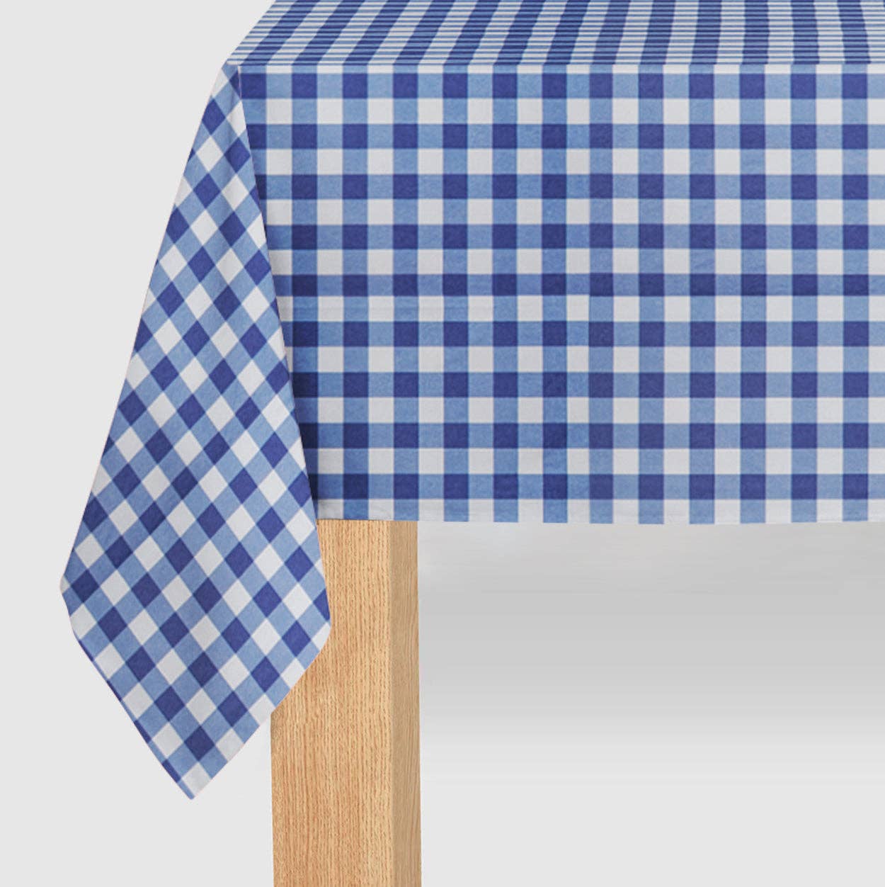 Close-up of a navy and white checkered paper tablecloth draped over a wooden table showing the soft paper texture.