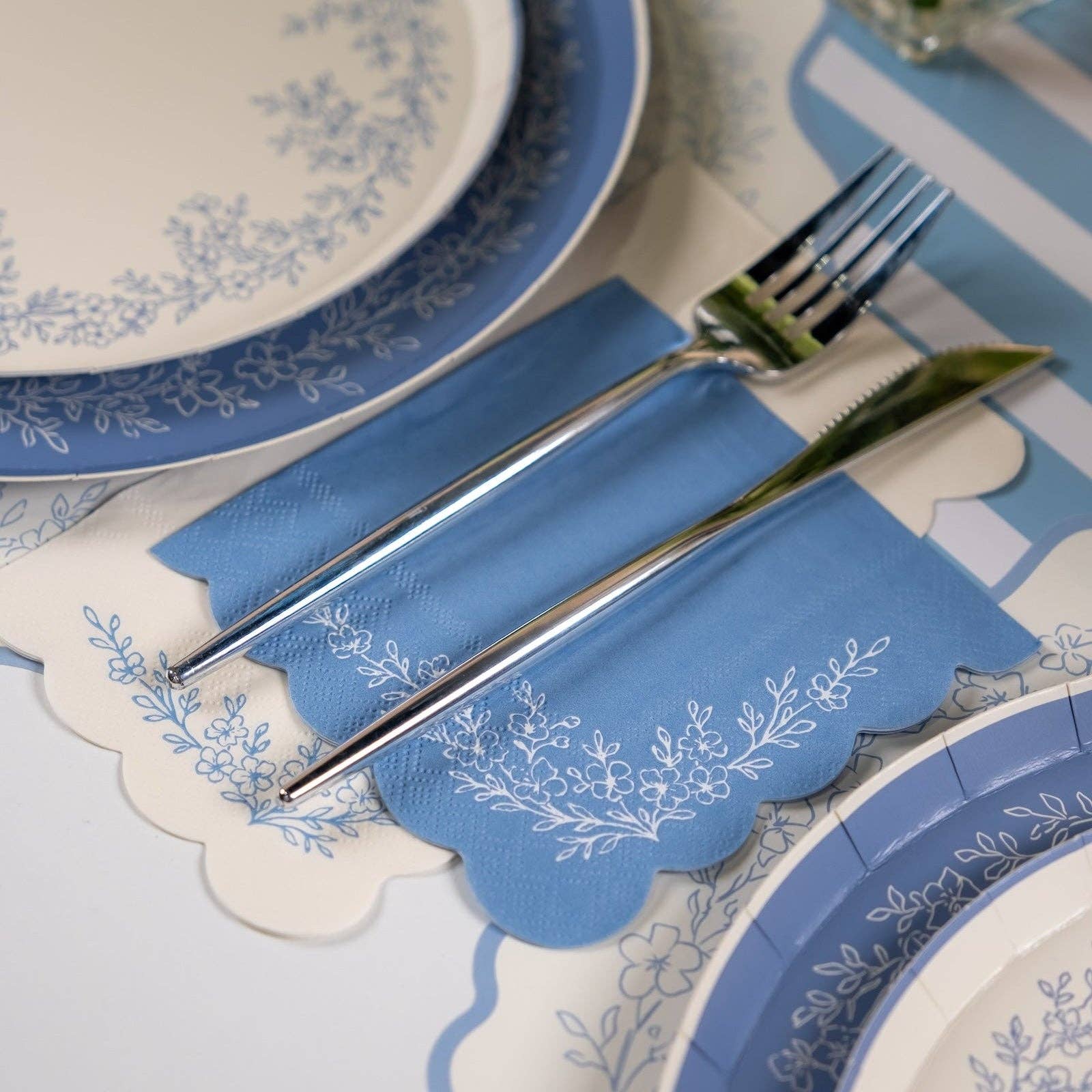 Blue floral guest towels styled with matching plates and blue napkins on table.
