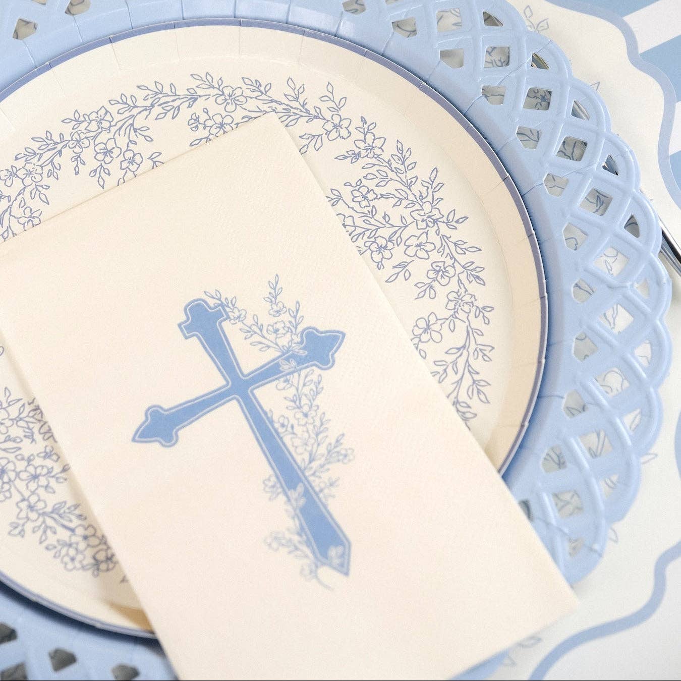 A detailed look at a light blue lattice edge plate with a hand painted style blue cross guest towel.