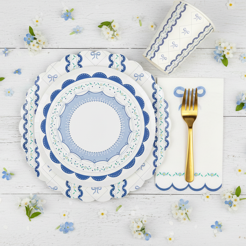 Overhead view of a blue bow cup next to stacked scalloped plates and a fork